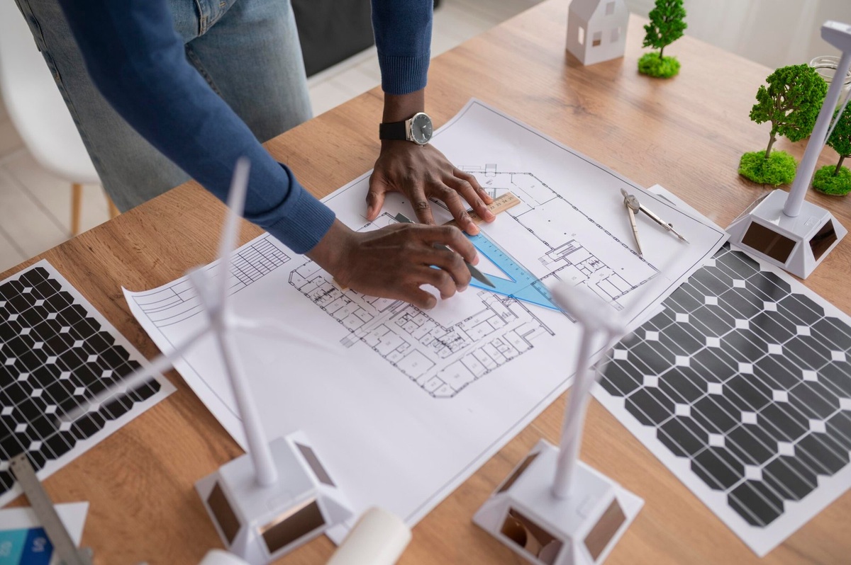 Plans techniques tracés à la règle, entourés de maquettes de panneaux et d'éoliennes