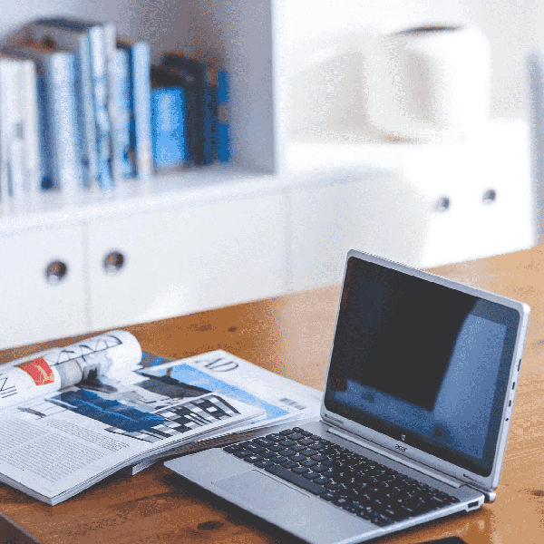 Ordinateur portable et revue ouverts sur une table en bois